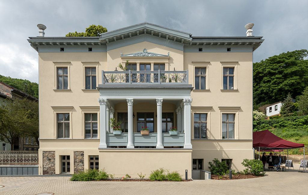 Frontalansicht eines zweigeschossigen Wohnhauses mit Balkon.